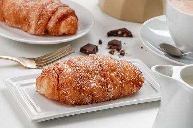 some xuixos de crema, pastries typical of catalonia, spain, filled with custard, on different white ceramic plates, on a table next to a cup of coffee clipart