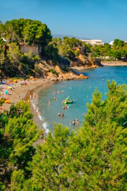 İspanya 'nın La Ampolla kentindeki Cap Roig plajında, gözde Costa Daurada sahillerinde, dikkatsiz insanların yaz gününün güzel havasının tadını çıkardıkları yerde.