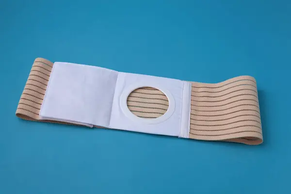 Stock image an unfolded abdominal belt with a stoma opening for colostomy patients on a blue background