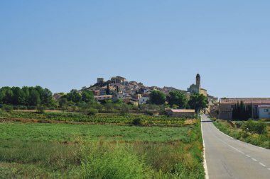 İspanya Katalonya 'nın tarihi bir köyü olan Barbera de la Conca' nın manzarası sağdaki Aziz Mary Kilisesi 'nin çan kulesini ve soldaki eski şatonun dairesel kulesini vurguluyor.