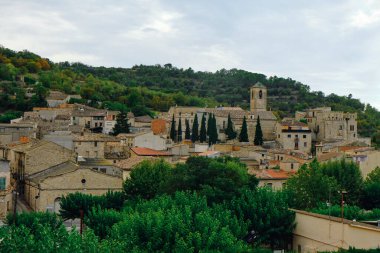 İspanya 'nın Katalonya kentindeki tarihi bir köy olan Vallfogona de Riucorb' un panoramik manzarası sağdaki Aziz Mary Kilisesi 'nin çan kulesini vurguluyor.