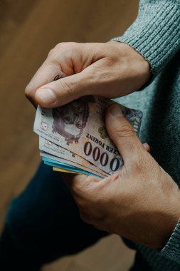 closeup of a man counting some hungarian forint notes indoors clipart