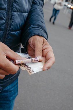 Bir Macar şehrinde elinde Macar formaları olan mavi bir kabarık ceketli bir adamın yakın çekimi.