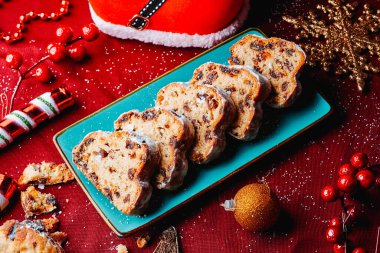 Dilimlenmiş bir noel çalgısı, kırmızı masa örtüsüyle yeşil bir tabakta servis edilir. Yanında da yılbaşı balosu ya da noel yıldızı gibi süsler vardır.