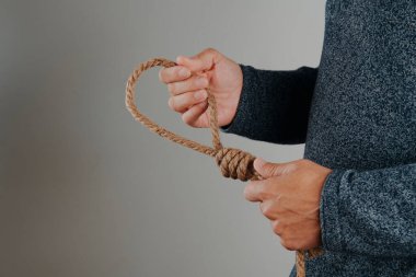 Bir adam, solunda boş bir alan olan gri bir arka planda kementle jüt bir ip tutuyor.