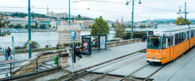 Budapeşte, Macaristan - 5 Ekim 2024: Budapeşte, Macaristan ve Budapeşte 'nin Pest bölgesinde Tuna Nehri' nden geçen bir tramvay, bir sonbahar günü, panoramik formatta