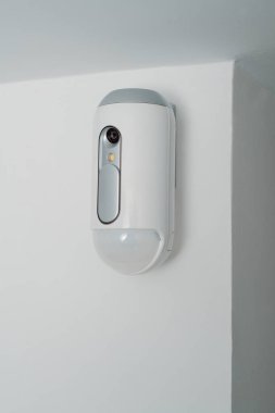 Kapalı mekandaki hırsız alarm sisteminin bir parçası olarak duvarda bir kamera bulunan hareket detektörüne yakın çekim.