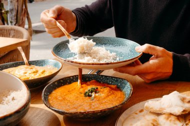 Tabakta bazmati pilavı servis eden bir adamın yakın plan fotoğrafı. Açık hava masasında farklı köri soslu tavuk ve tavuk tikka masala gibi.