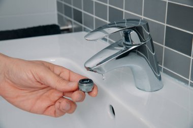 Bir adam, tuvaletteki havalandırmayı lavabonun musluğundan çıkarmış. Kireçlenme birikimini çıkarmak için.