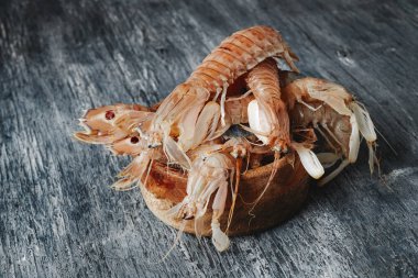 İskandinav dilinde galeriler olarak bilinen, gri ahşap bir masada, mantid karidesli ahşap bir kase.