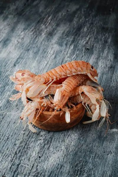 biraz İspanyol galerası, squilla mantid (peygamberdevesi), bir tür peygamber devesi karidesi, ahşap bir kase üzerinde gri bir ahşap masa üzerine yerleştirilmiş