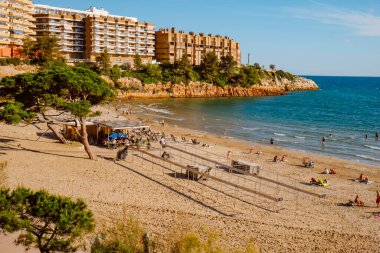 Salou, İspanya - 11 Mayıs 2025: Bazı insanlar güneşli bir pazar günü İspanya 'nın Salou kentindeki Capellans Plajı' nda hoş havanın tadını çıkarıyorlar
