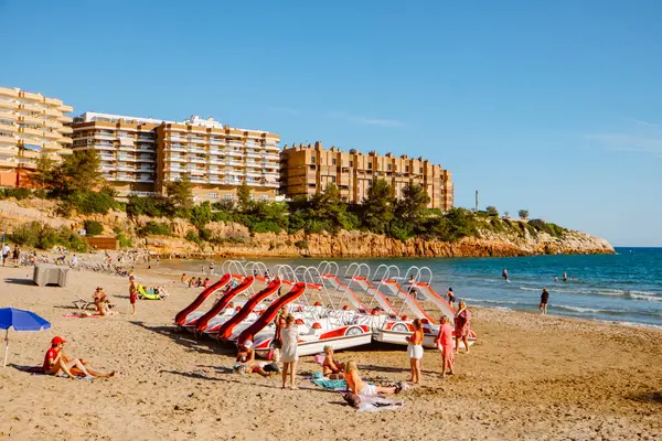 Salou, İspanya - 11 Mayıs 2025: Güneşli bir bahar gününde, Salou 'da kayalıklarla çevrili derin bir koy olan Capellans Beach' te kiralık pedal teknelerinin yanındaki insanlar