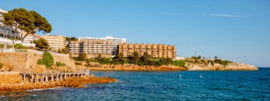 İspanya 'nın başkenti Salou' da, Capellans Sahili 'nin kıyısında Cami de Ronda olarak bilinen kıyı yolu ile deniz üzerinde asılı duran tahta bir yaya köprüsünü geçerken panoramik bir manzara.