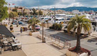 Cannes, Fransa - 9 Mayıs 2025: Cannes Eski Limanı 'ndaki Quai Saint-Pierre, rıhtım boyunca demirlemiş yatlar, solda belediye binası ve sağda görünen beyaz film festivali çadırları