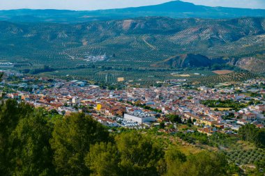 İspanya 'nın Endülüs eyaletinin Malaga eyaletinde güneşli bir bahar gününde dağların ve zeytinliklerin arasına kurulmuş küçük bir kasaba olan Cuevas de San Marcos' un hava manzarası.