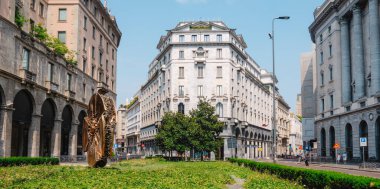Milan, İtalya - 21 Haziran 2025: Piazza Filippo Meda 'da, büyük bir bronz disk heykeli Via Pietro Verri ve Corso Matteotti yakınlarındaki neoklasik ve modern binalar arasında cesurca duruyor.