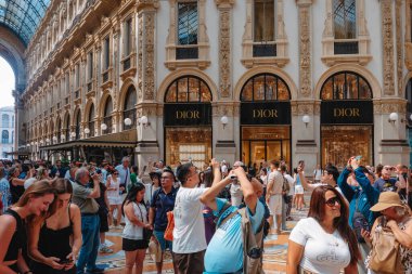 Milan, İtalya - 21 Haziran 2025: Milano 'daki Galleria Vittorio Emanuele II' yi ziyaretçiler, lüks mağazalara hayran olmak ve tarihi cam ve demir atari salonunun altında fotoğraf çekmek için durdular.