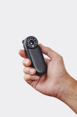 Bir adam elinde siyah pille çalışan bir vantilatörle kendini serinletir. Tarafsız bir arkaplana karşı, yakın çekim stüdyo çekiminde.