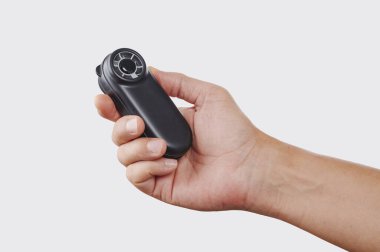 Batarya destekli küçük bir vantilatör kullanan bir adamın yakın plan fotoğrafı. Kendini yenilerken düz beyaz bir stüdyo arka planına karşı yandan tutuyor.