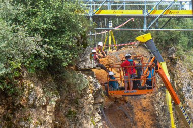 Atapuerca, İspanya - 12 Temmuz 2025: Kask takan arkeologlar Sierra de Atapuerca sahasındaki kayalık bir yamaçta antik çökelti katmanlarını kazmak için iskele ve asansörleri kullanıyorlar