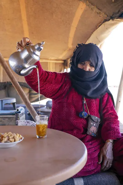 MERZOUGA, MOROCCO - 3 HAZİRAN 2024: Berber kadın Fas 'ın Merzouge çölündeki bir kampta misafirler için çay hazırlıyor.