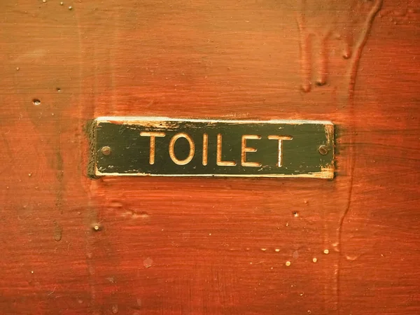 old toilet sign on a wooden door