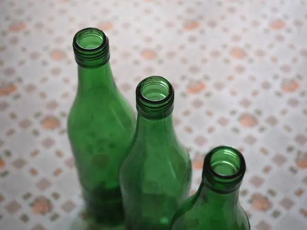 コピースペース付きのテーブルの上に3つの空の緑のワインボトル — ストック写真