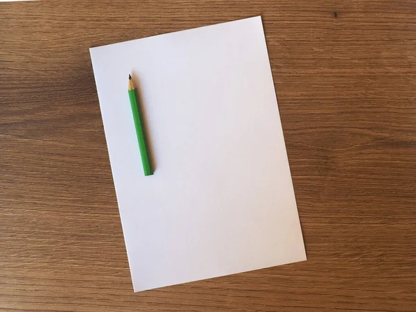 Grüner Bleistift Auf Leerem Papierbogen Auf Hölzernem Schreibtisch Mit Kopierraum — Stockfoto