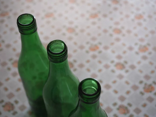 コピースペース付きのテーブルの上に3つの空の緑のワインボトル — ストック写真