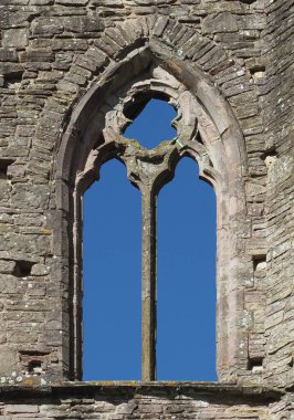 Gotik, mavi gökyüzü ile taştan bir duvarda süzülmüş pencere.