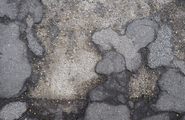 asphalt damage on derelict pavement floor showing underlying concrete slab useful as a background