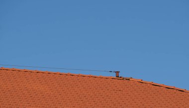 Mavi gökyüzünün üstündeki çatıda güvenlik halatı