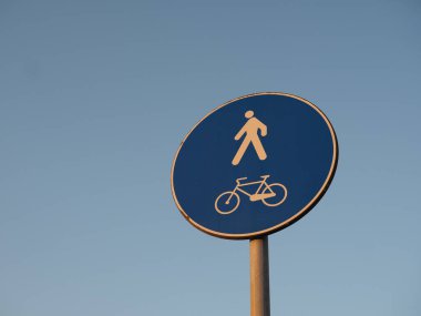 Mavi gökyüzünün üzerinde yaya bölgesi ve bisiklet yolu tabelası