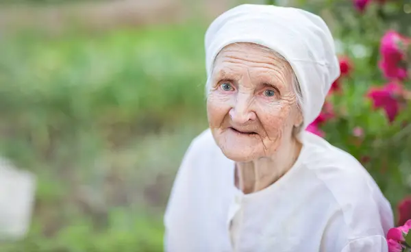 Portrait of senior woman outdoors. Aged lady looking up at camera and smiling.