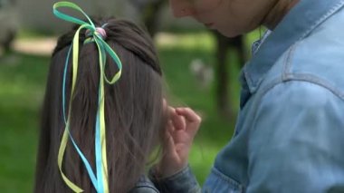 Ukrayna 'nın mavi ve sarı bayrağındaki geleneksel Ukrayna çelenklerinde anne ve kızı. Aile, birlik, destek. Ukraynalılar savaşa karşıdır. Kadın ve çocuk. Ukrayna 'ya özgürlük. Rus saldırısını durdurun..