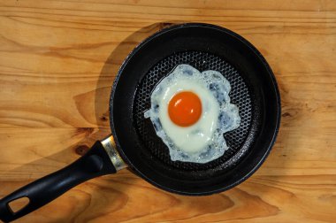 Smiling Happy Face Frying Eggs breakfast with parsley in iron vintage pot on wooden table. Selective focus