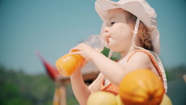 Little Girl Wearing Orange Clothes Drinks Orange Juice — Stock Video