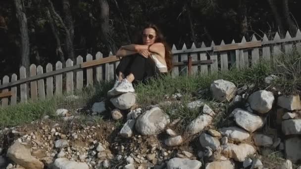 一个年轻女子坐在海滨岩石边的空中拍摄 — 图库视频影像