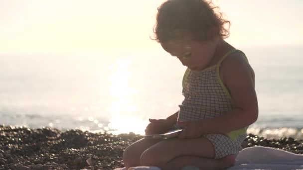 重点女婴在海滩上使用智能手机 — 图库视频影像
