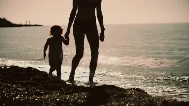 一个母亲和她的小宝宝在海滩上散步的轮廓 — 图库视频影像