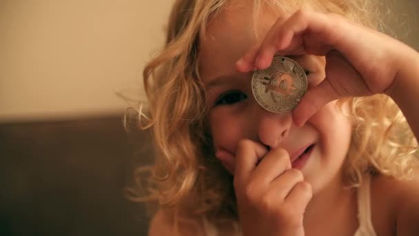 美しい金髪の少女はビットコインで遊びます — ストック動画