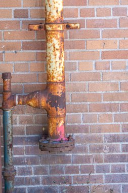 Sarı paslanmış paslı borular kırmızı tuğla bir duvarda.