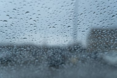 Otoparkta arabanın ön camına yağmur damlaları düşer.