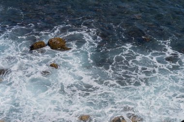 Okyanus kıyısındaki kayalar bulutlarla kaplı.