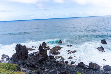Okyanus kıyısındaki kayalar bulutlarla kaplı.