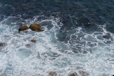 Okyanus kıyısındaki kayalar bulutlarla kaplı.