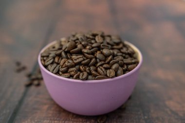 Pembe bir kabın içindeki organik doğal kahve çekirdekleri.