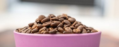Pembe bir kabın içindeki organik doğal kahve çekirdekleri.