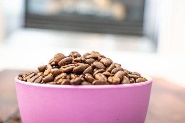 Pembe bir kabın içindeki organik doğal kahve çekirdekleri.